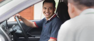 portrait of asian male car driver talking to someone from his car window.