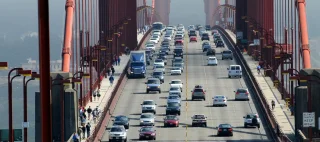Zoom of heavy traffic on Golden Gate Bridge, connecting San Francisco to Marin County, warm air rising from road and cars in the front.