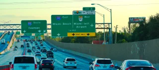 Miami, Florida, USA - January 1, 2020: Traffic to South Florida's Miami Beach landmark and Miami International Airport green interstate 195 highway exit sign driving instructions with sun pass toll.