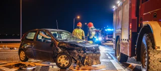 Road accident. Ambulance and fire truck with emergency lights. A black passenger car was destroyed in a head-on accident. Firefighters at the scene of the accident