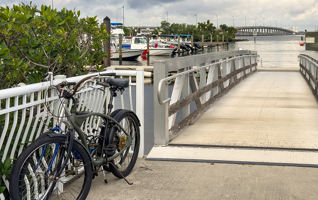 Two bicycles parked together by entrance ramp at a riverside marina in Punta Gorda, Florida, with a view of the northbound US 41 traffic bridge across Peace River, on a cloudy day in southwest Florida – Punta Gorda, cheap car insurance in Florida