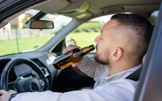 Man drinking alcohol while driving a car.
