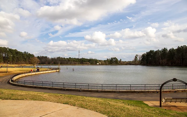 A gorgeous winter landscape at Rhodes Jordan Park with a blue lake, yellow winter grass lush green trees, people walking and blue sky with powerful clouds at sunset in Lawrenceville Georgia USA – Lawrenceville, cheap car insurance in Georgia