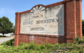 Welcome sign for the city of Anniston, Alabama, standing proudly against a vibrant blue sky, cheap car insurance in Alabama.