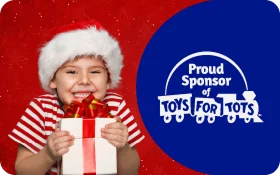 A smiling child wearing a Santa hat and striped sweater holds a wrapped gift in front of a red festive background with text that says “Donate Today – Brighten a child’s holiday! Click here for a list of participating locations,” and the Toys for Tots logo on the right.