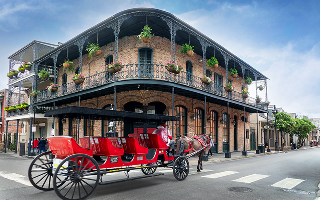 Sightseeing Horse Carriage tour and a typical building with balconies and columns in a street of the French Quarter, New Orleans, Louisiana
