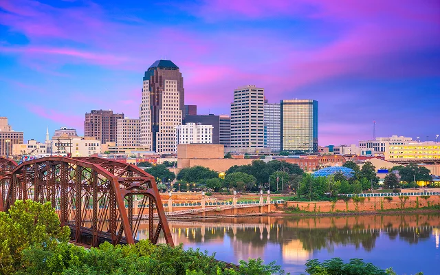 Shreveport, Louisiana skyline at sunset with Red River and steel bridge in the foreground – Shreveport, cheap car insurance in Louisiana.