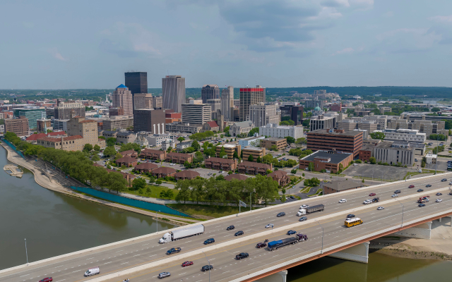 Aerial view of downtown Dayton, Ohio, with the city skyline, Great Miami River, and highway traffic in the foreground.