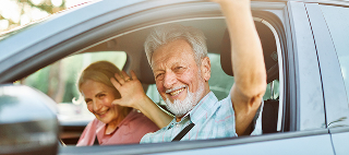 Happy senior couple going on a trip in their car.